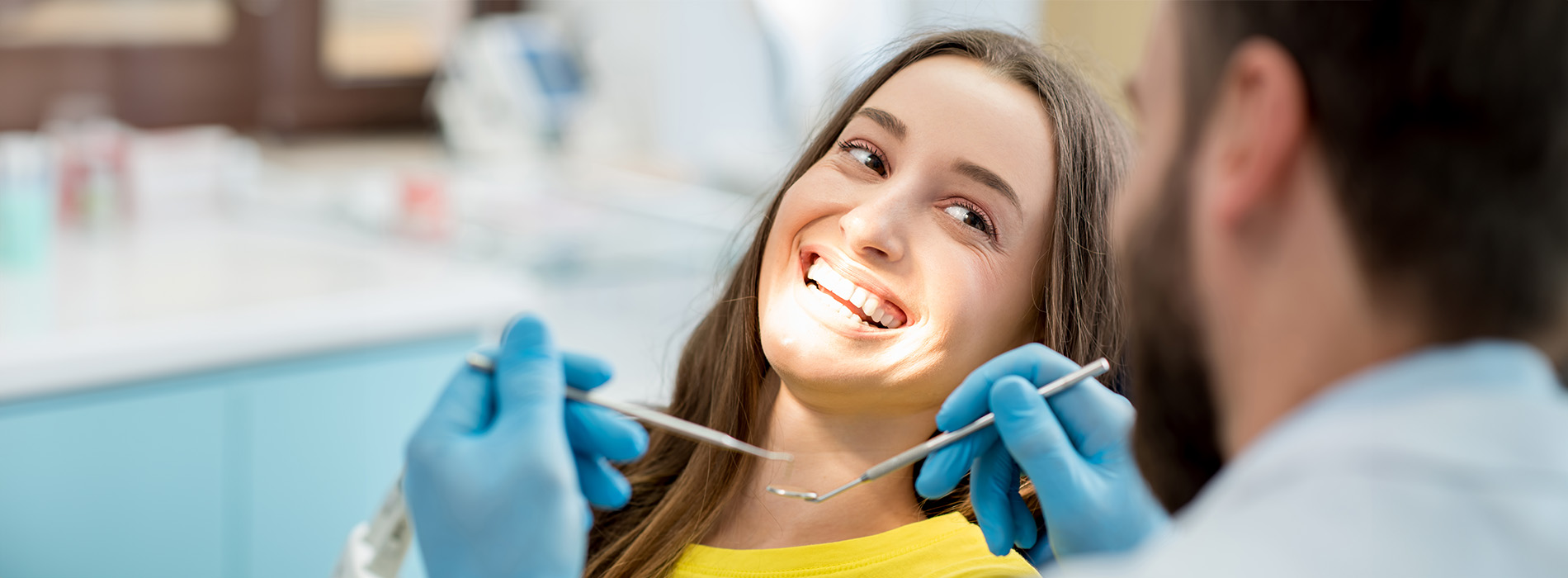 The image shows a dental professional performing an oral examination on a patient in a dental clinic setting.
