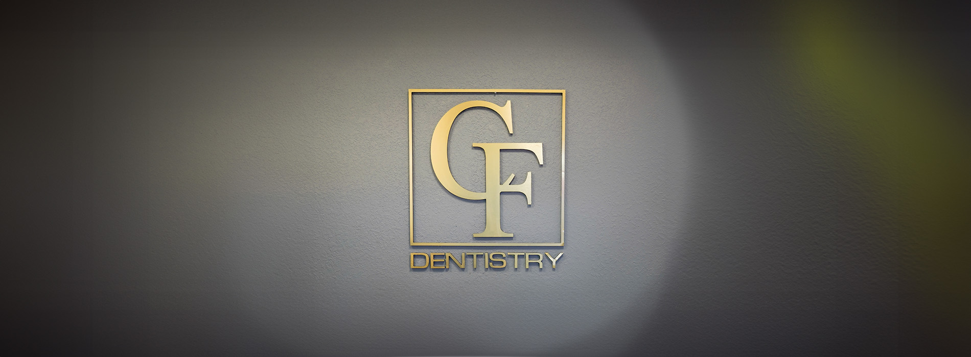 The image shows a group of people, possibly professionals given their attire and the setting that appears to be an office or professional environment. They are gathered around a table with a laptop on it, engaged in what seems to be a discussion or meeting.