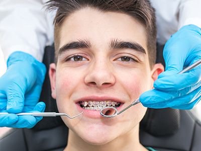 A young man receiving dental treatment with a dental hygienist assisting him.