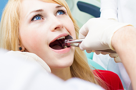 A young woman receiving dental care with a dentist performing a procedure on her teeth.